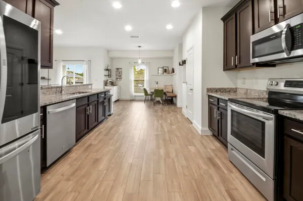 a large kitchen with stainless steel appliances granite countertop a stove and a wooden floors
