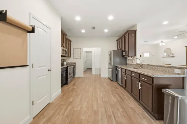 a kitchen with stainless steel appliances granite countertop a lot of counter space and wooden floors