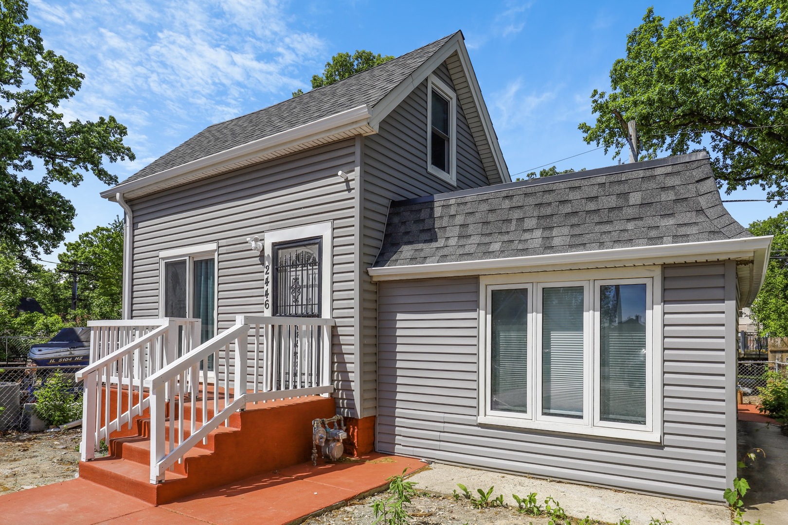 a view of a house with a small deck and a large tree