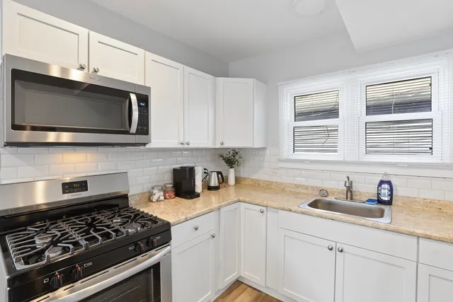 a kitchen with stainless steel appliances granite countertop white cabinets a stove a sink and dishwasher