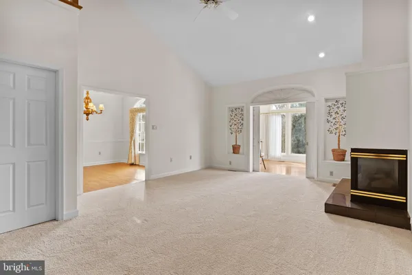 a view of an empty room with chandelier fan and fire place