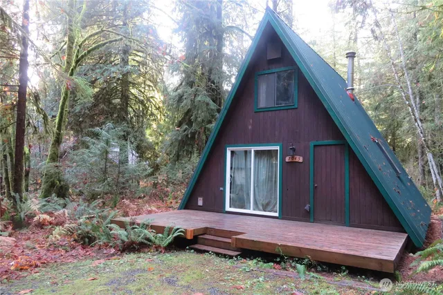 a view of a small house with a small yard plants and large tree