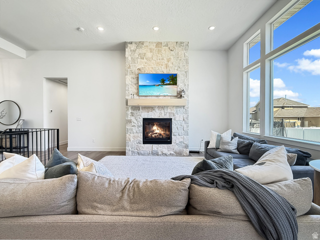 916 Rocky Mountain Way Elk Ridge, UT 84651 - Photo 11 of 54 Living room featuring a stone fireplace, wood finished floors, recessed lighting, and a textured ceiling