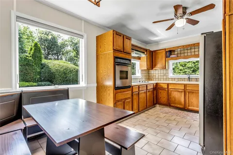 a kitchen with stainless steel appliances granite countertop a stove a refrigerator a sink a dining table and chairs with the outer view