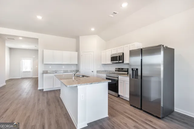 a kitchen with a sink a refrigerator and a stove top oven