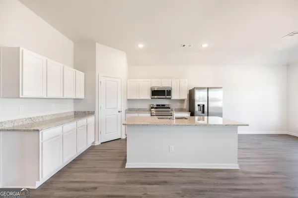 a kitchen with stainless steel appliances a stove top oven a sink and white cabinets