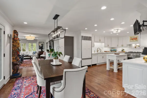 a kitchen with stainless steel appliances kitchen island granite countertop a dining table chairs stove and white cabinets