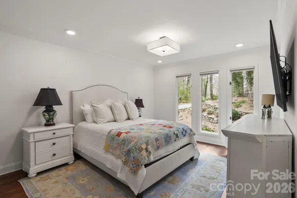 a bedroom with a large bed and a flat tv screen on dresser