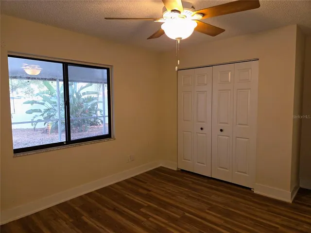 a view of a room with wooden floor fan and windows