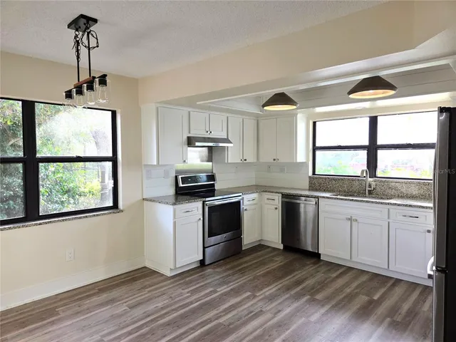 a kitchen with appliances cabinets a large window and a sink