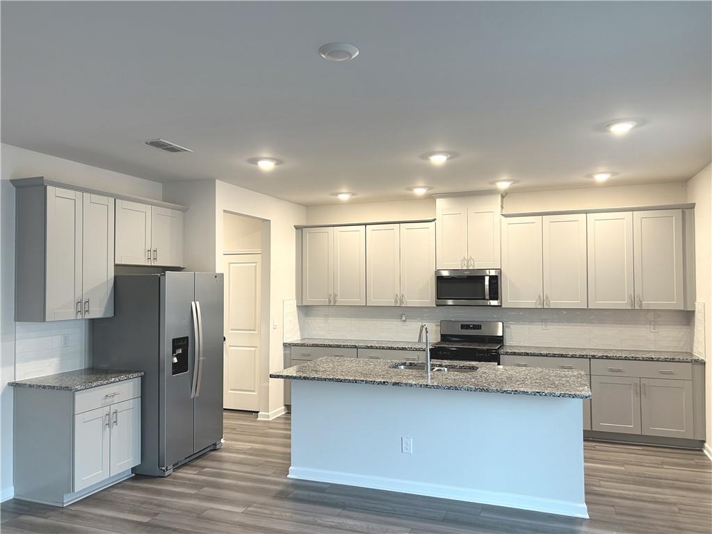 6901 Durham Lane Fairburn, GA 30213 - Photo 7 of 29 a kitchen with stainless steel appliances granite countertop a refrigerator a stove a sink and white cabinets with wooden floor