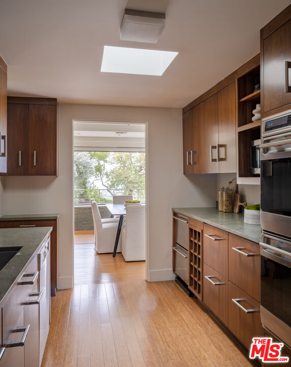 1575 Carla Ridge Beverly Hills, CA 90210 - Photo 18 of 39 a kitchen with stainless steel appliances wooden floor sink and wooden cabinets