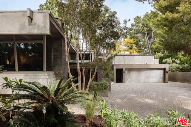 a view of a house with potted plants and large trees