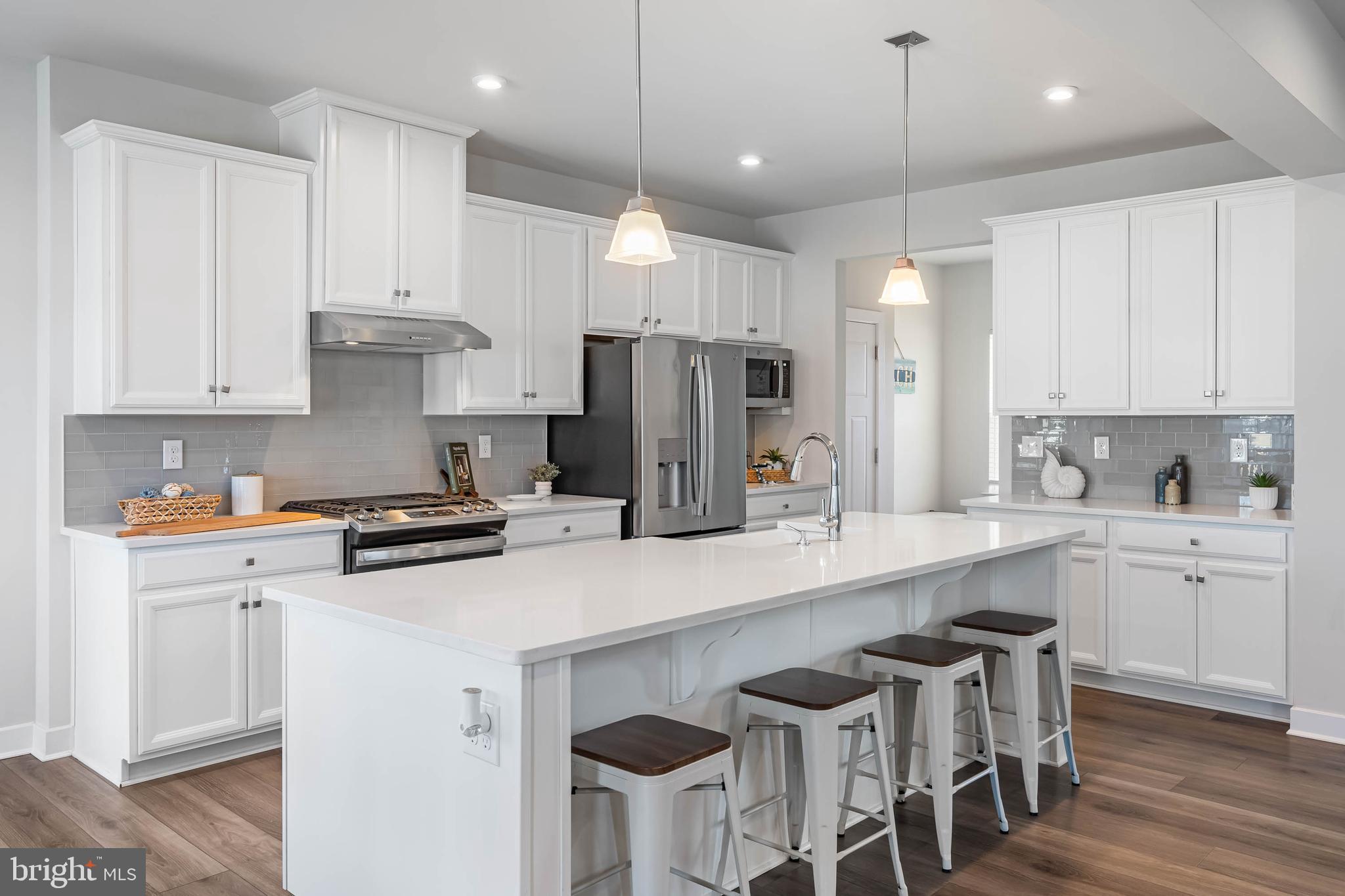 19079 Trimaran Drive Lewes, DE 19958 - Photo 12 of 61 a kitchen with stainless steel appliances a stove a sink a refrigerator and white cabinets with wooden floor