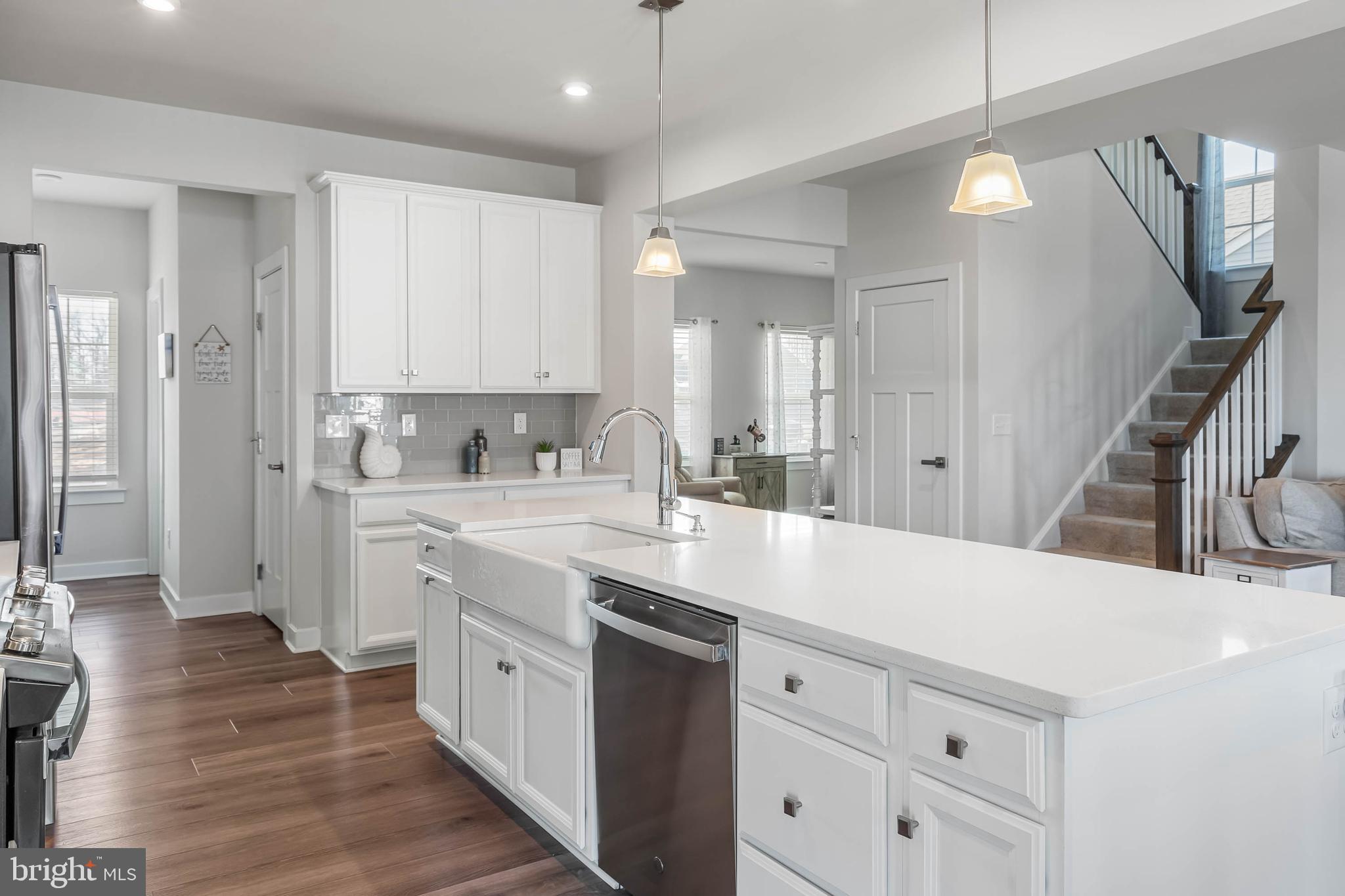 19079 Trimaran Drive Lewes, DE 19958 - Photo 14 of 61 a kitchen with a sink dishwasher a stove and white cabinets with wooden floor