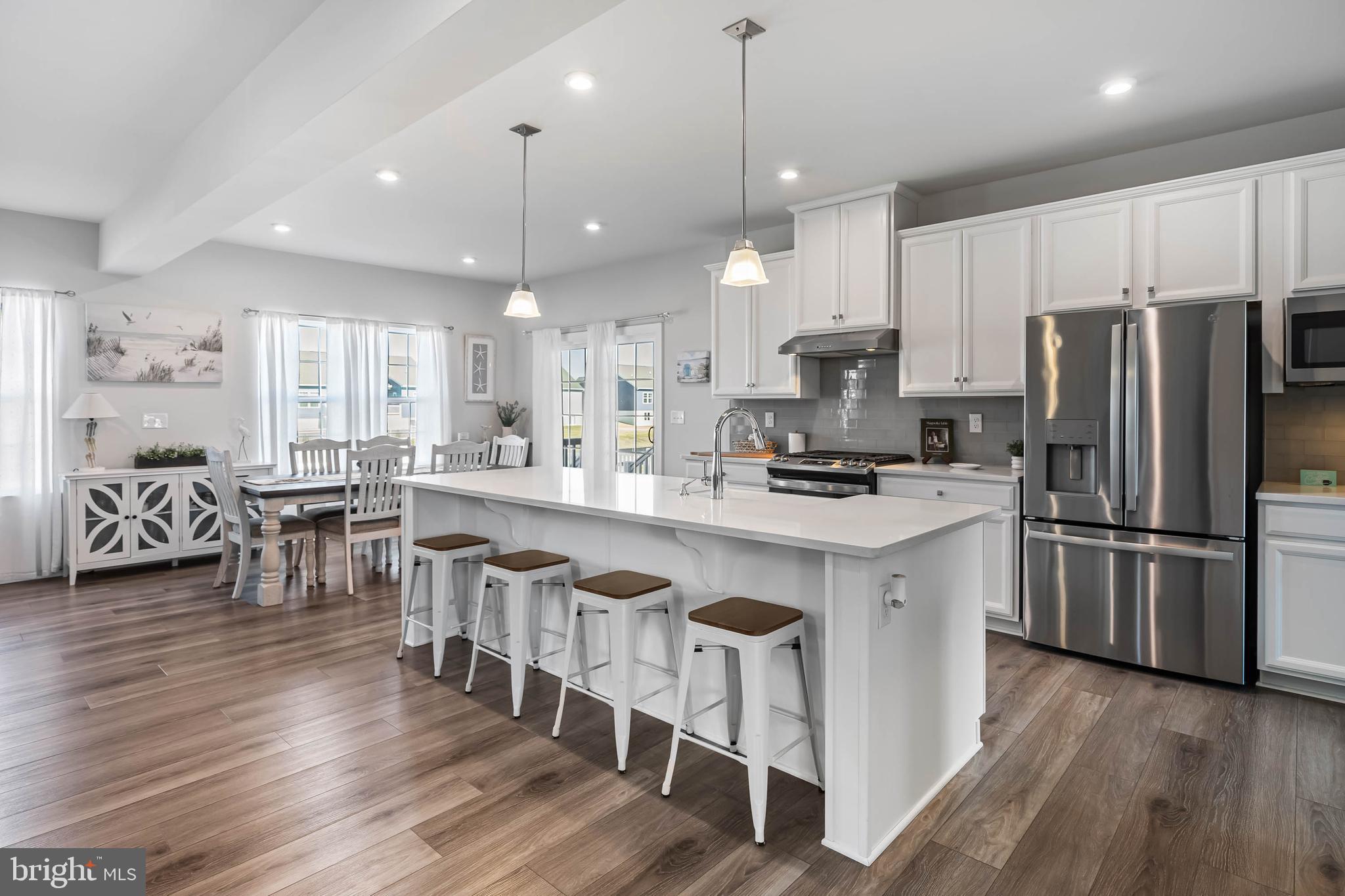 19079 Trimaran Drive Lewes, DE 19958 - Photo 10 of 61 a kitchen with stainless steel appliances granite countertop a refrigerator a stove top oven a sink dishwasher a dining table and chairs with wooden floor