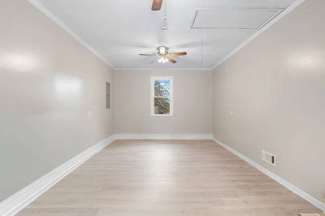 an empty room with wooden floor ceiling fan and windows