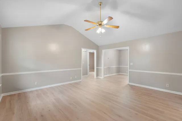an empty room with wooden floor fan and windows