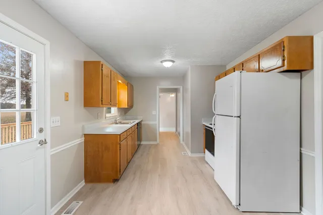 a large kitchen with a refrigerator a sink dishwasher and a stove with wooden floor