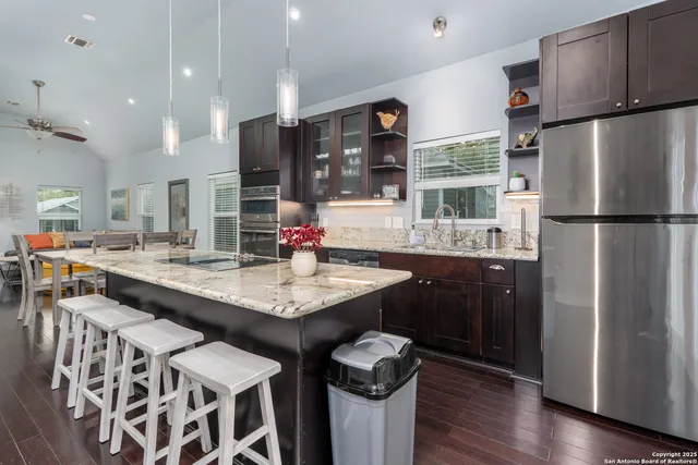 a kitchen with stainless steel appliances granite countertop a sink a stove a refrigerator and a refrigerator