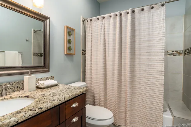 a bathroom with a granite countertop sink vanity mirror and toilet