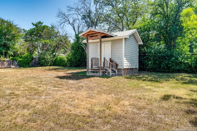 a front view of house with yard and trees in the background