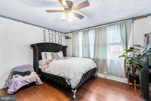 a bedroom with a bed potted plant on the dresser and a large window