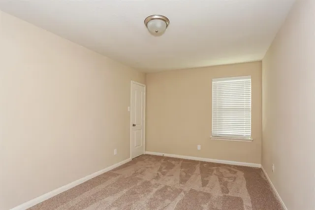 a view of an empty room with window and closet area