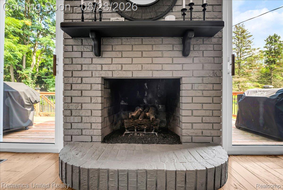 3687 Van Amberg Road Brighton, MI 48114 - Photo 7 of 56 Brick-finish fireplace with a hearth, mantel, and wood-finish flooring