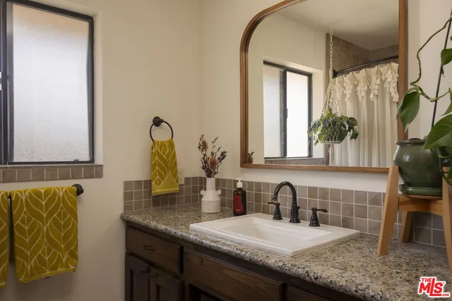 a bathroom with a granite countertop sink a mirror and shower