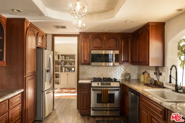 a kitchen with stainless steel appliances granite countertop a refrigerator a stove a sink and a microwave