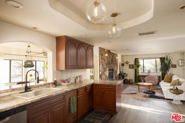 a large kitchen with a large counter space a sink appliances and cabinets