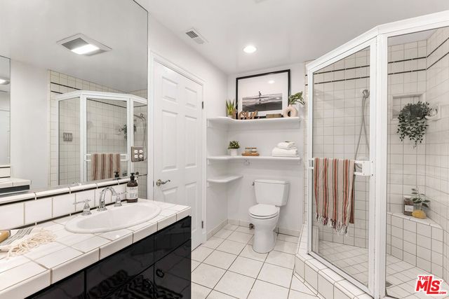 a bathroom with a granite countertop sink a toilet a mirror and shower