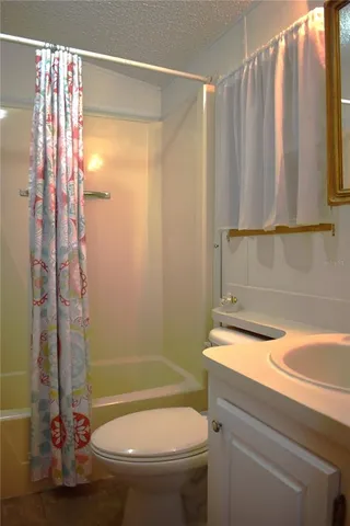 a bathroom with a granite countertop bathtub shower and a toilet