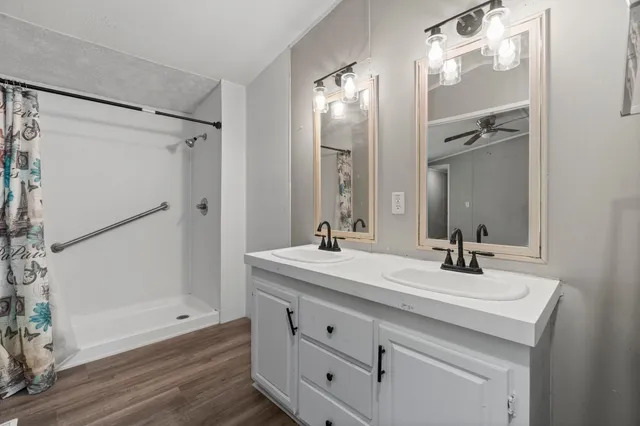 a bathroom with a bathtub shower sink vanity and mirror