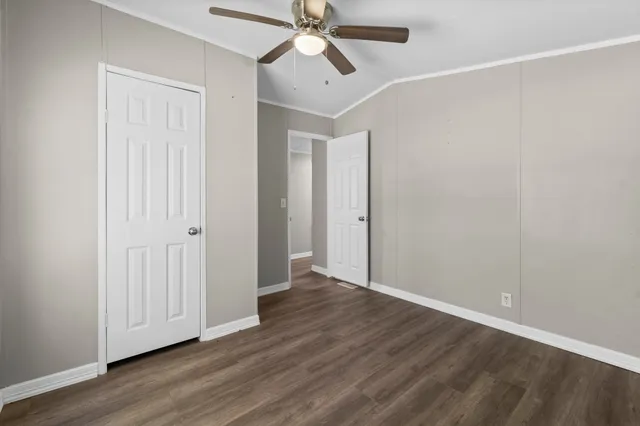 an empty room with wooden floor ceiling fan and windows