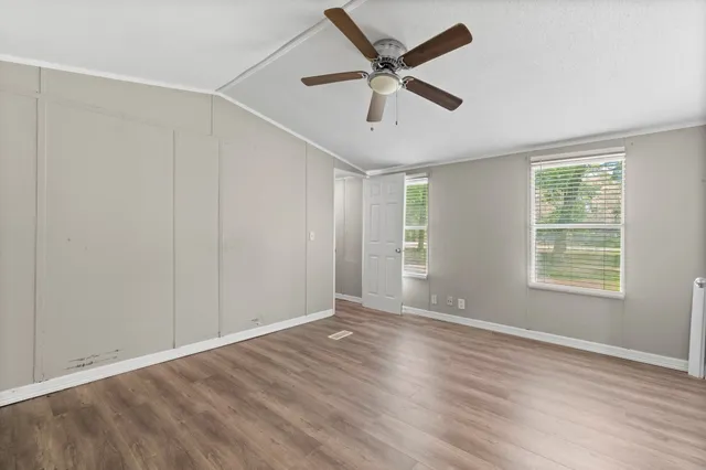 an empty room with wooden floor and windows