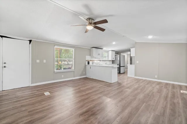a view of an empty room with window and wooden floor