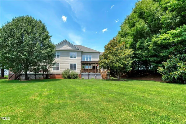 a view of a house with a big yard and large trees