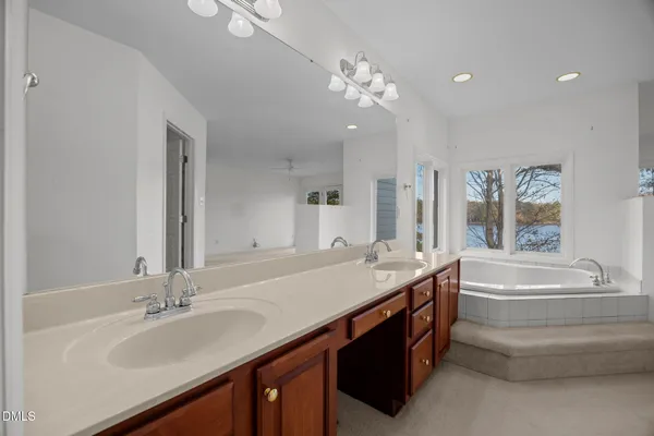 a spacious bathroom with a granite countertop double vanity sink a mirror and a bathtub