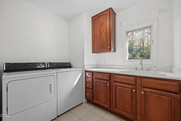 a utility room with stainless steel appliances white cabinets and a sink