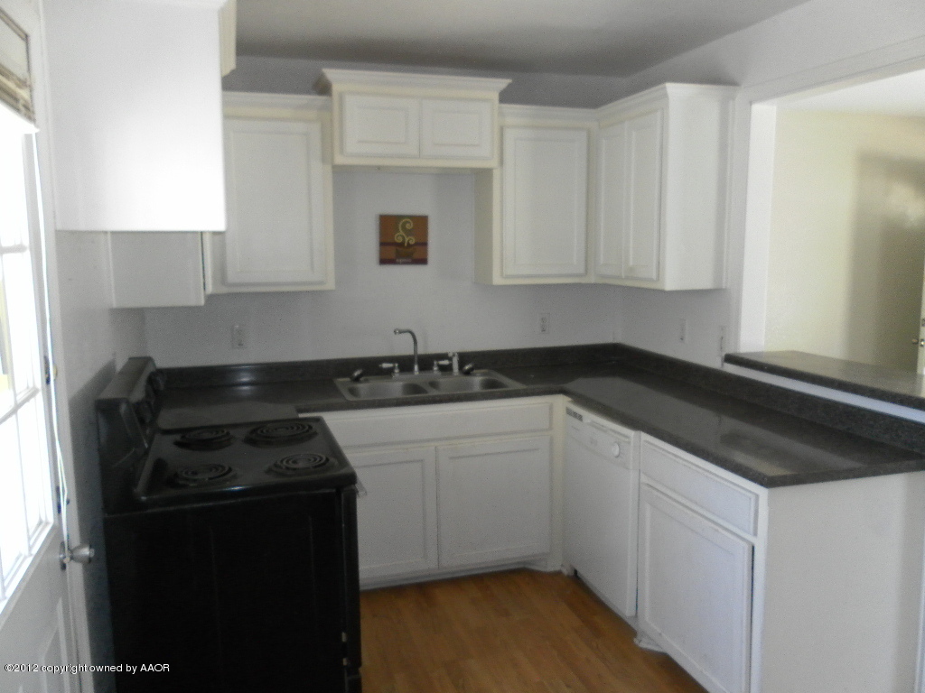 4313 South Polk Street Amarillo, TX 79110 - Photo 7 of 10 a kitchen with granite countertop white cabinets and black appliances