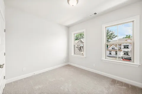 an empty room with windows and refrigerator