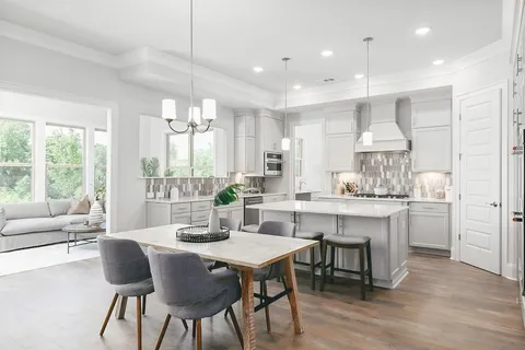 a kitchen with kitchen island granite countertop a table chairs sink and cabinets