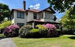 a front view of a house with a yard and potted plants