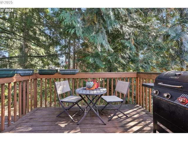 a balcony with wooden floor outdoor seating and trees in the background