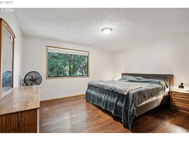 a bedroom with a bed a dresser and windows