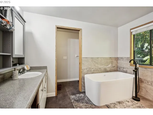 a bathroom with a granite countertop tub sink and mirror