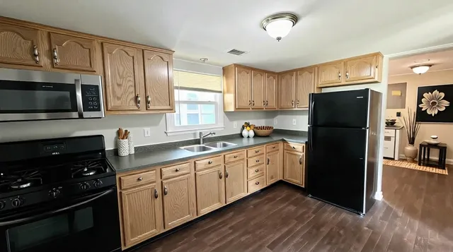 a kitchen with granite countertop a refrigerator stove top oven and sink