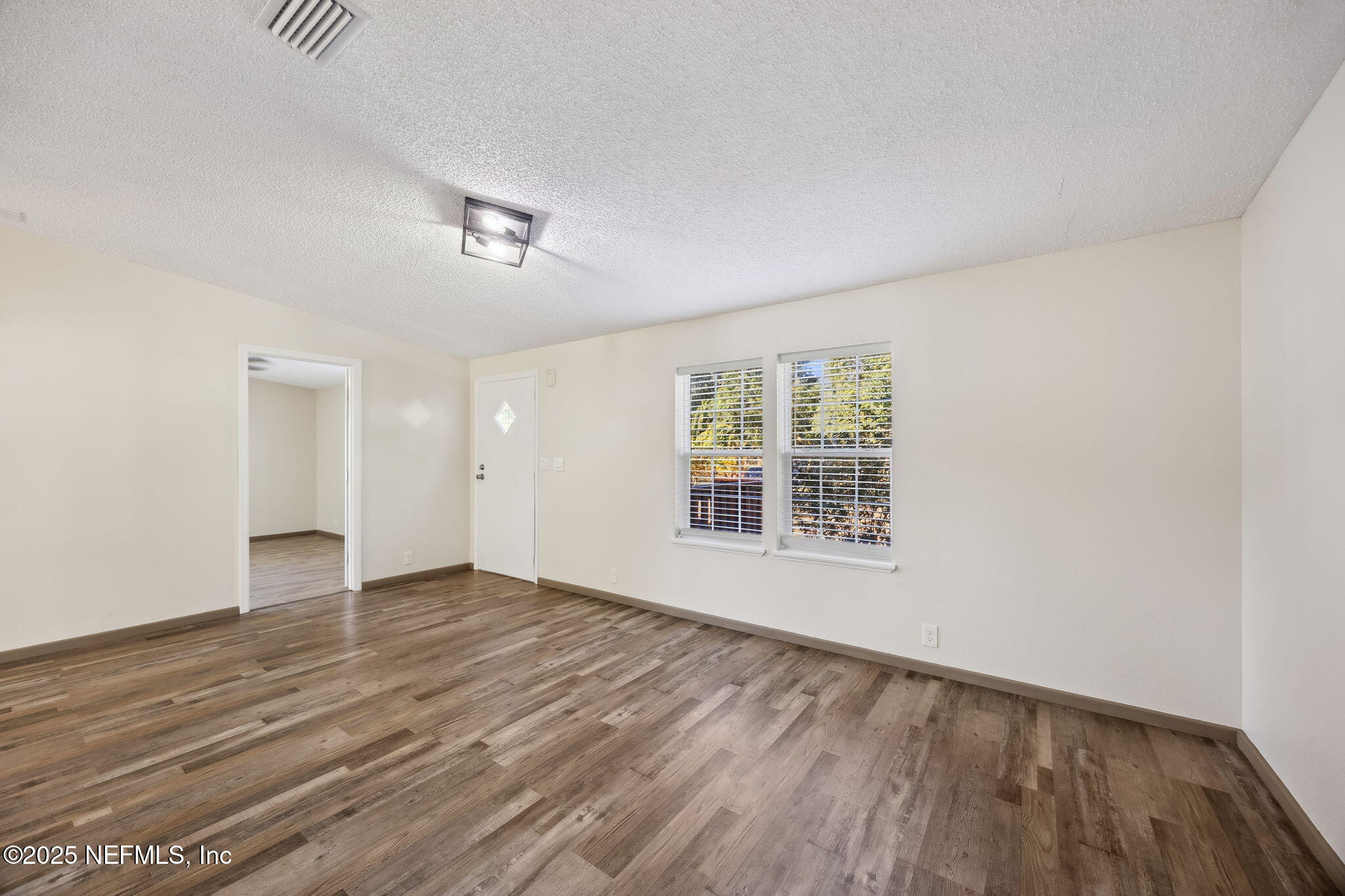 6034 Leona Padgett Road Jacksonville, FL 32234 - Photo 11 of 37 an empty room with wooden floor and windows